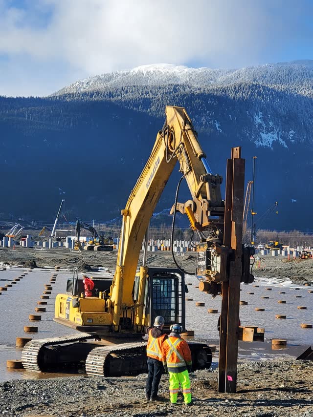 Excavator-mounted vibratory hammer installing sheet piles