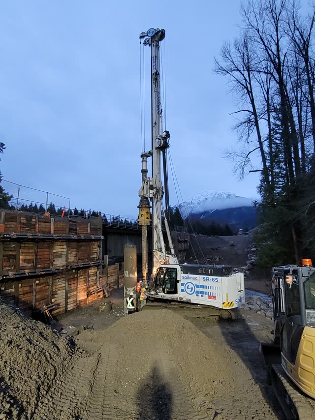 Drill rig working near a riverbank at dusk