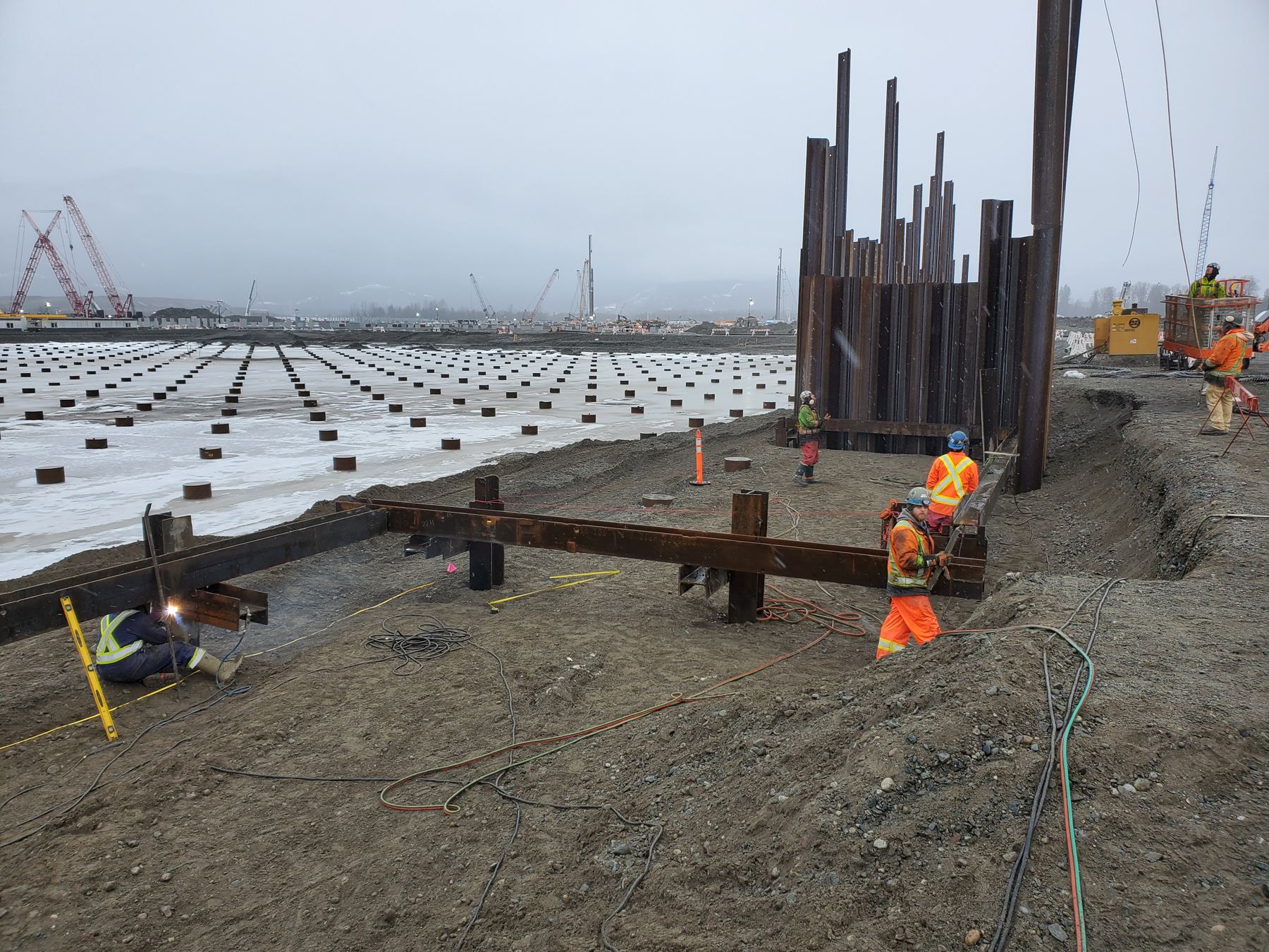 Large LNG pile field with sheet-pile shoring and welding crews