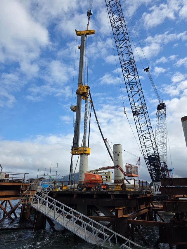 Marine piling rig drilling a rock socket through casing on an over-water platform