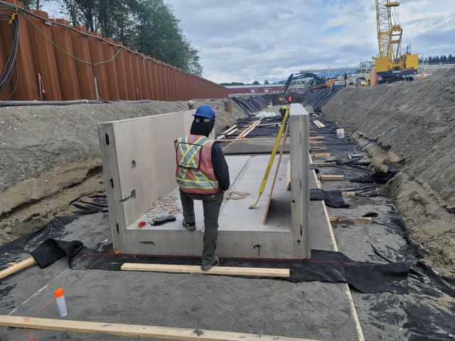 Precast concrete units set in a shored trench alongside a sheet-piled wall