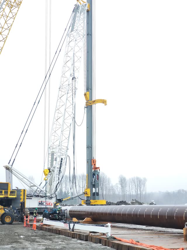 Pipe pile hoisted into crane leads before driving