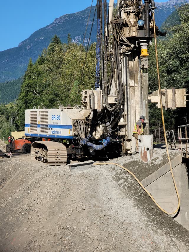 Tracked drill rig and support truck working in mountainous terrain