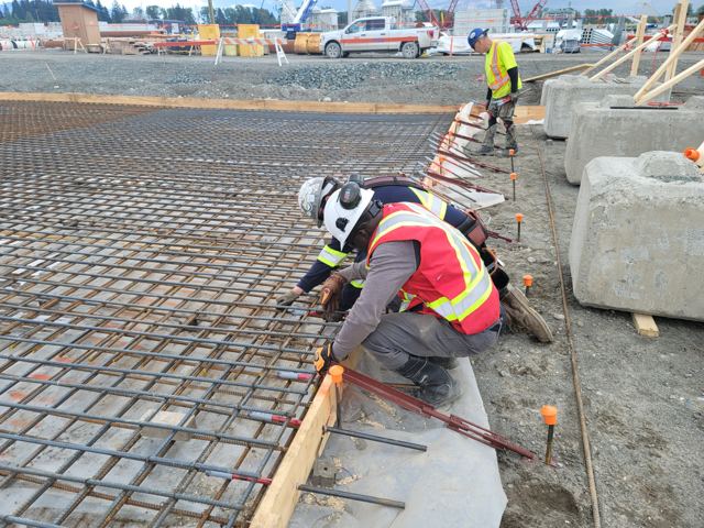 Crew tying reinforcing mat and dowels ahead of a foundation slab pour